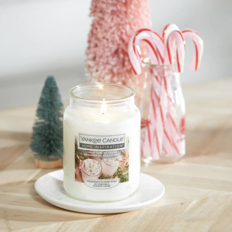 Yankee Candle candle on a wooden surface with candy canes and a small Christmas tree in the background.